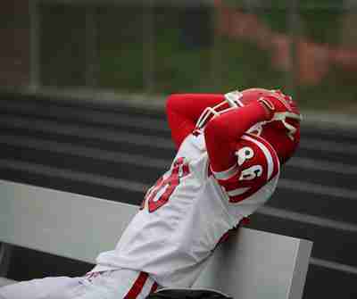 Football player on the bench with his hands on his head in defeat