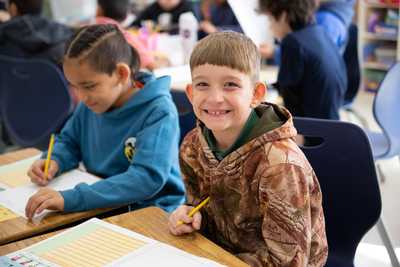 Elementary student sitting at desk, smiling at the camera