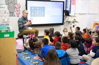 Adult volunteer asking a question to a group of elementary school students in a classroom