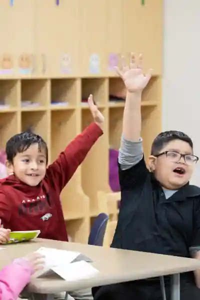 Adult volunteer asking a question to a group of elementary school students in a classroom